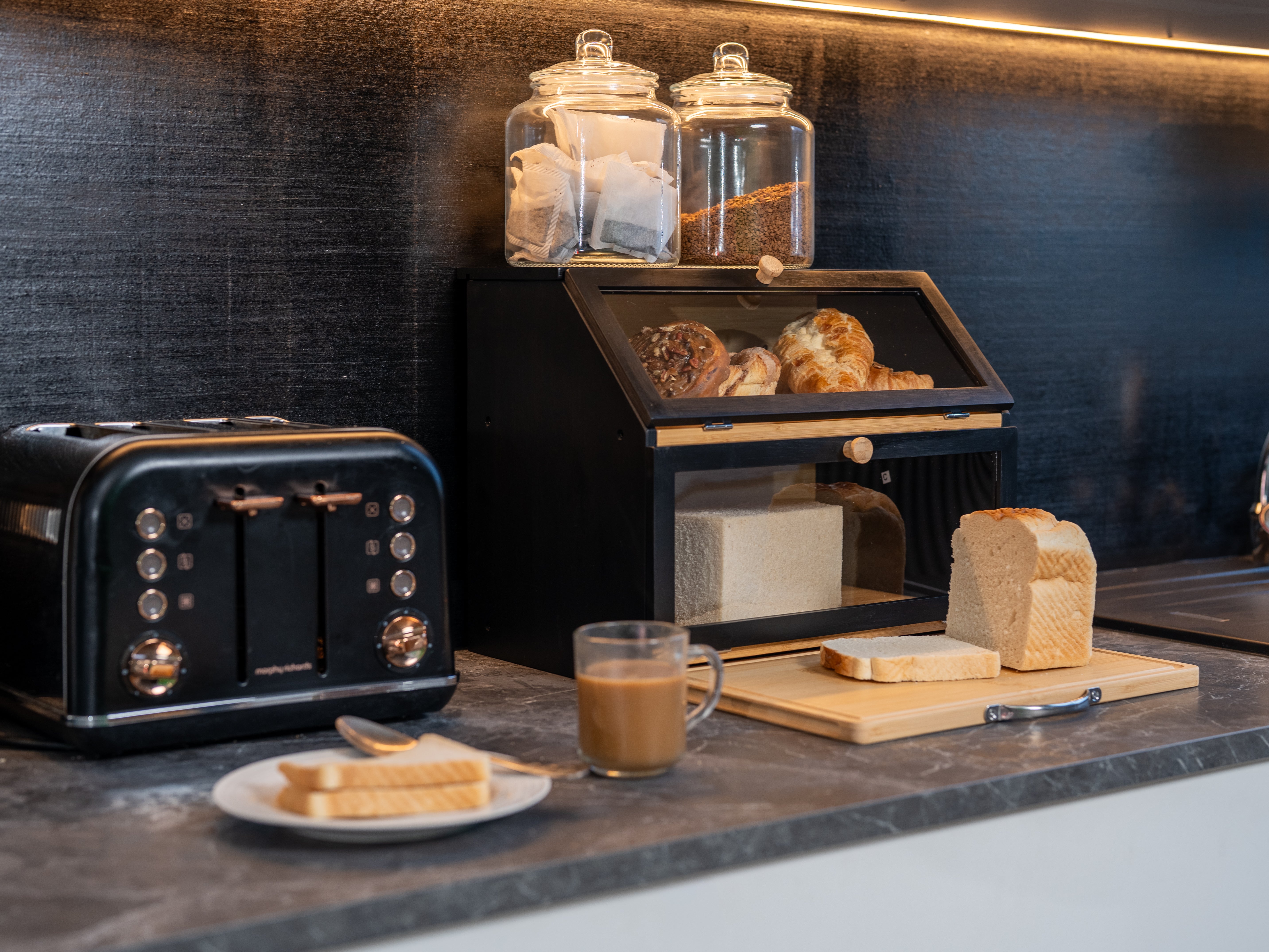 Kitchen counter with a toaster, coffee cup, and bread display case.